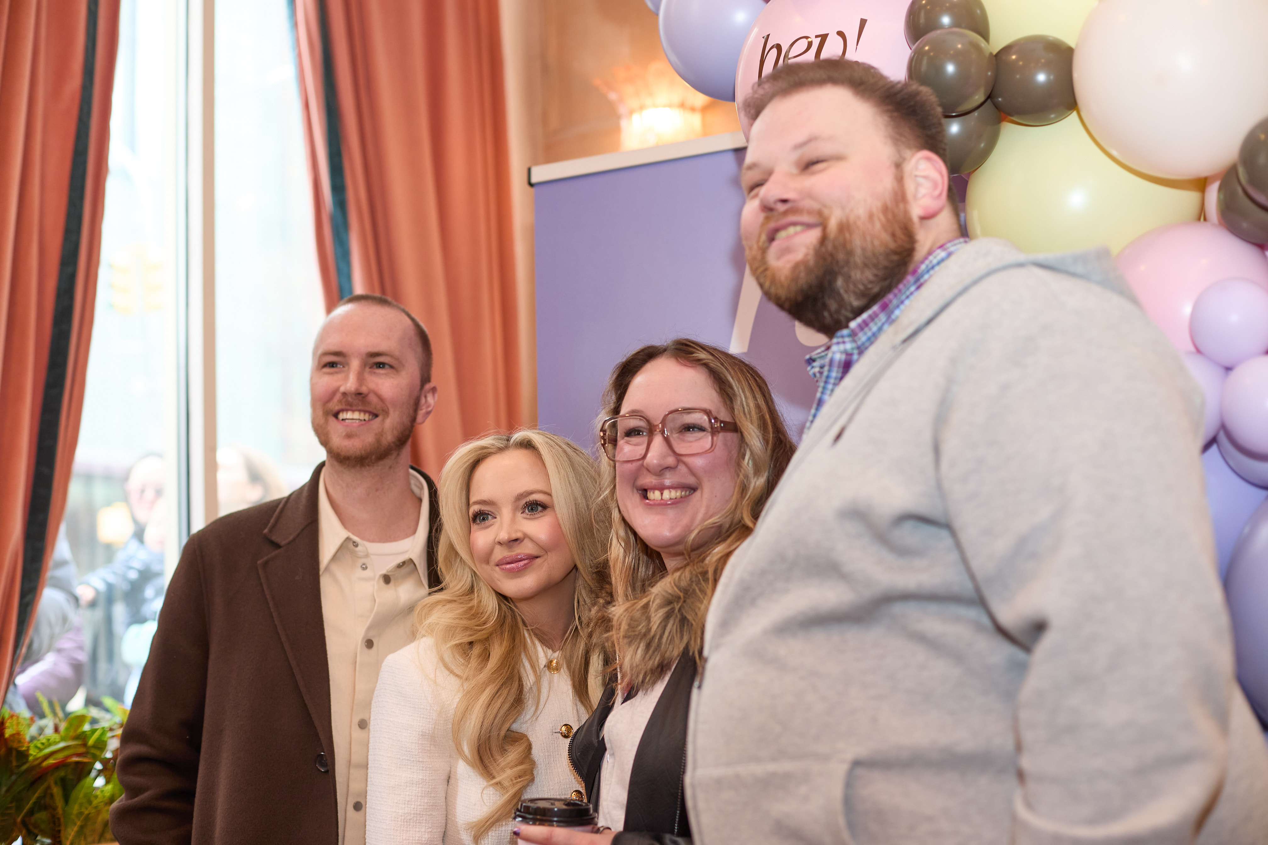 Kay and Tay Dudley with two people posing for a photo in front of a colorful balloon arch.
