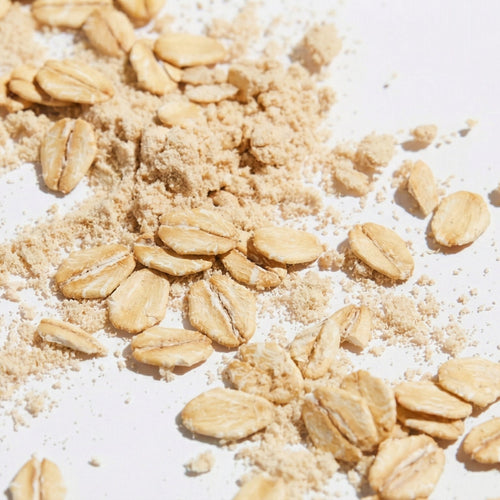 Oats and oat protein powder scattered on a white surface